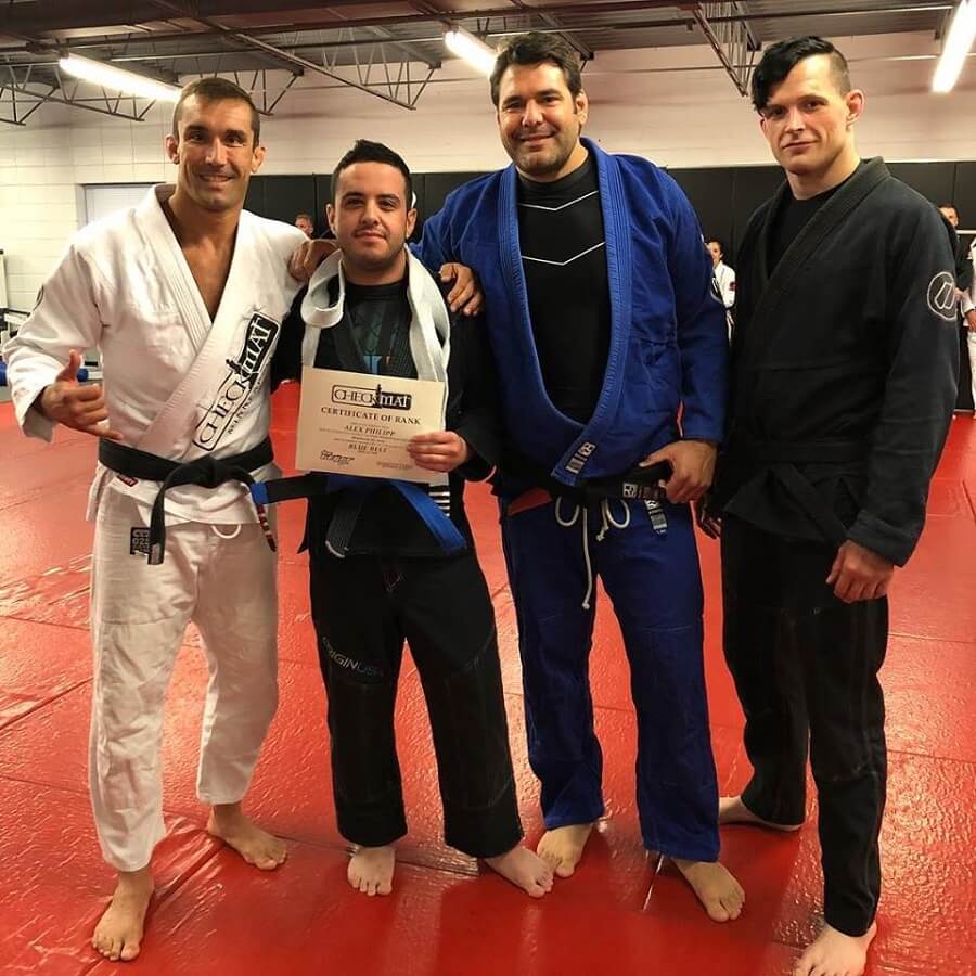 Three Brazilian jiu jitsu black belts with newly promoted blue belt